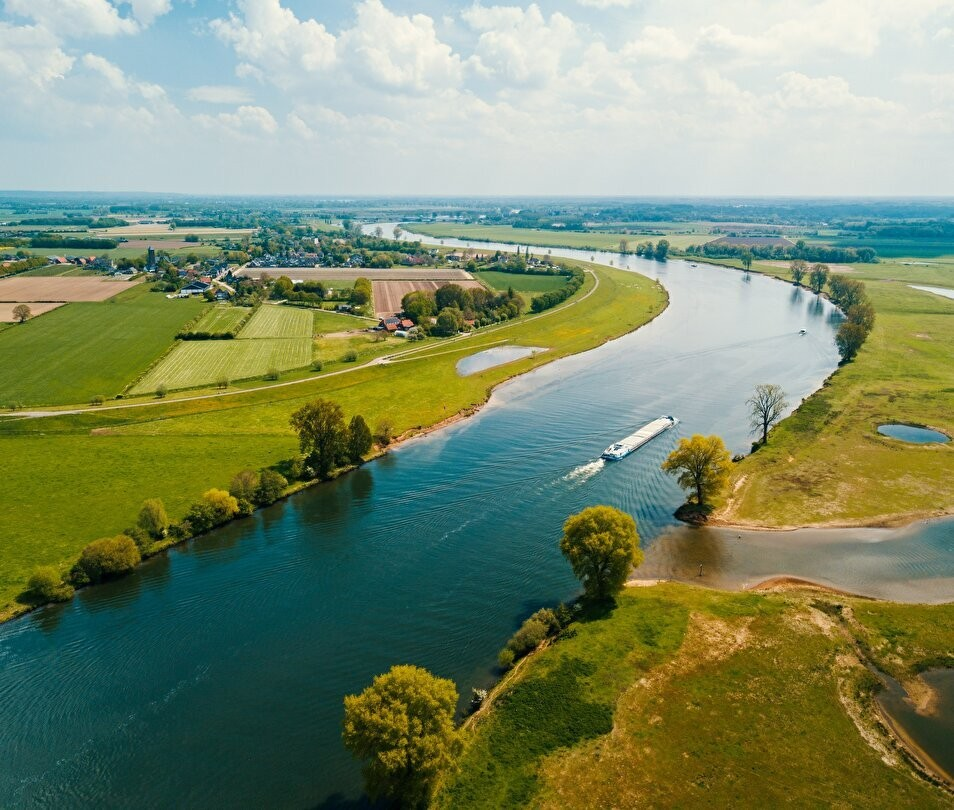 Foto van een rivierbocht met groen landschap eromheen.